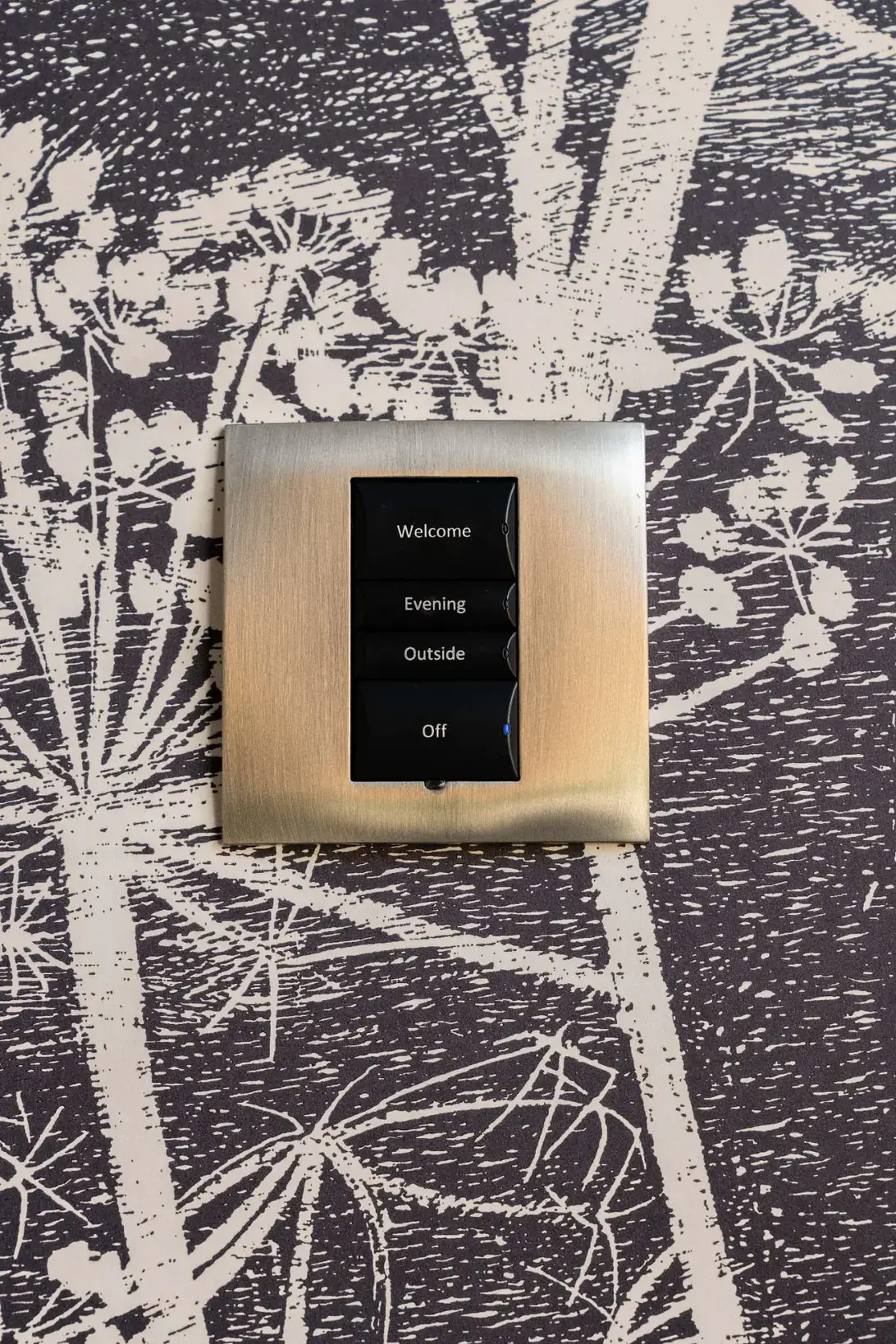A brass lighting keypad with scenes labelled Welcome, Evening, Outside and Off